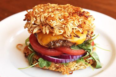 Cheeseburger with baby greens and sliced tomato and red onion, sandwiched between two pan-fried ramen "buns" 