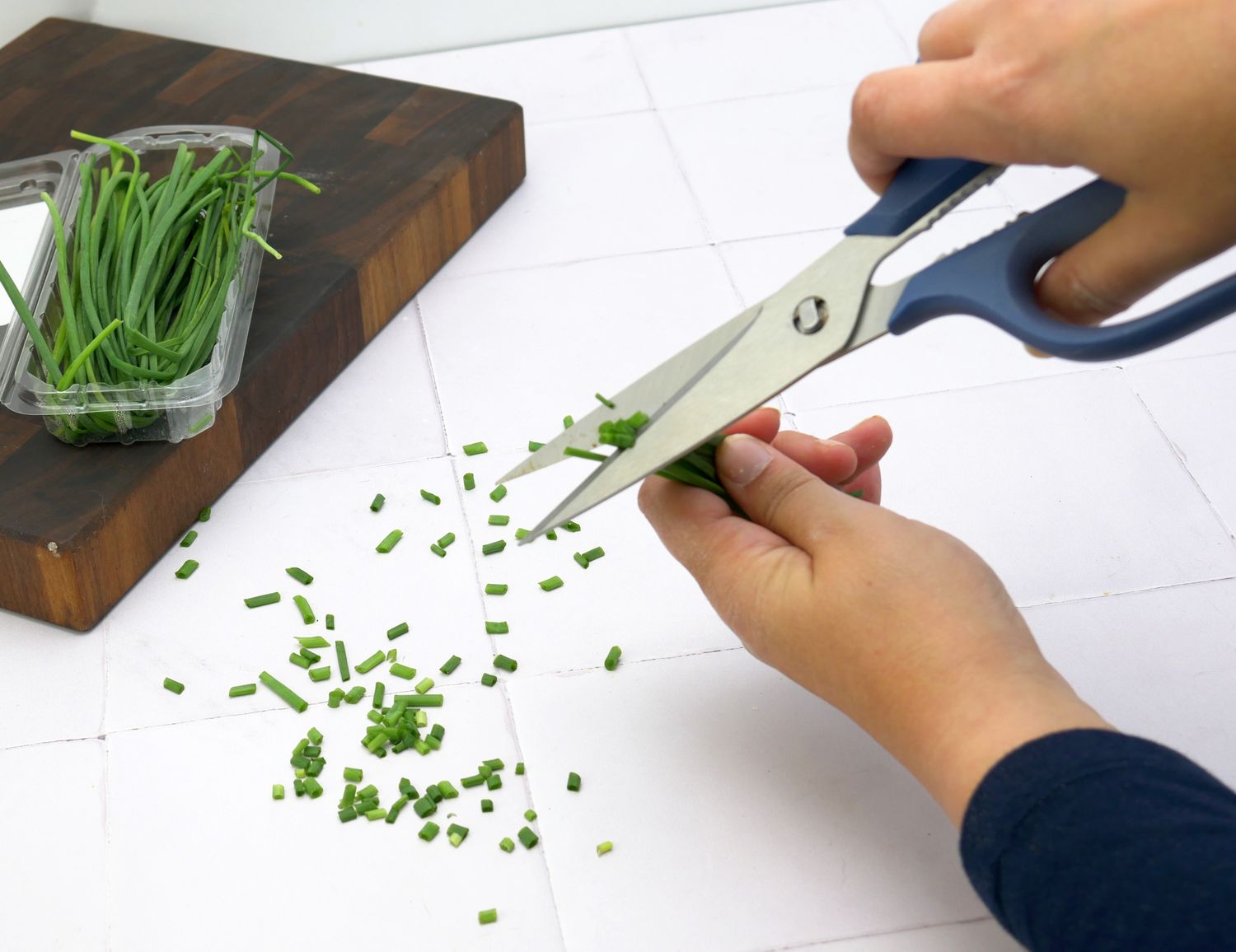 a person cutting chives with kitchen shears