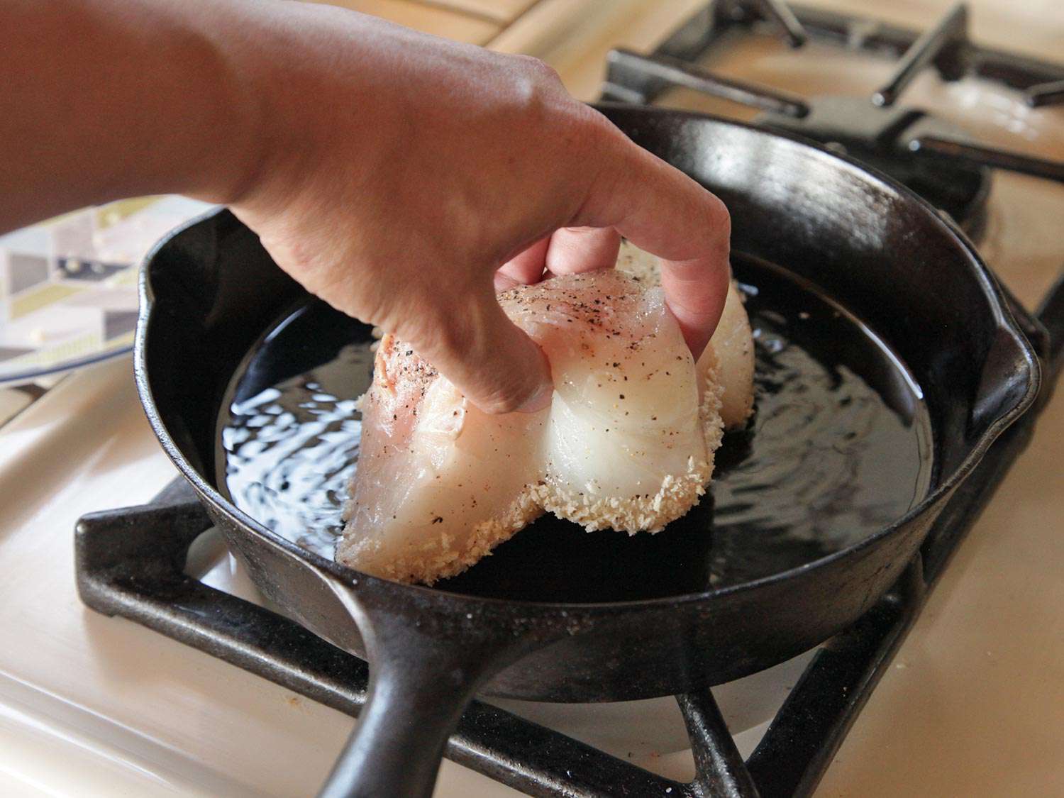 The fillet portions are added to shallow-fry in a cast iron skillet, breaded side down.