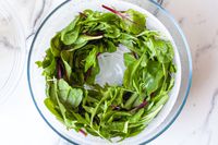 greens in the bowl of the oxo glass salad spinner