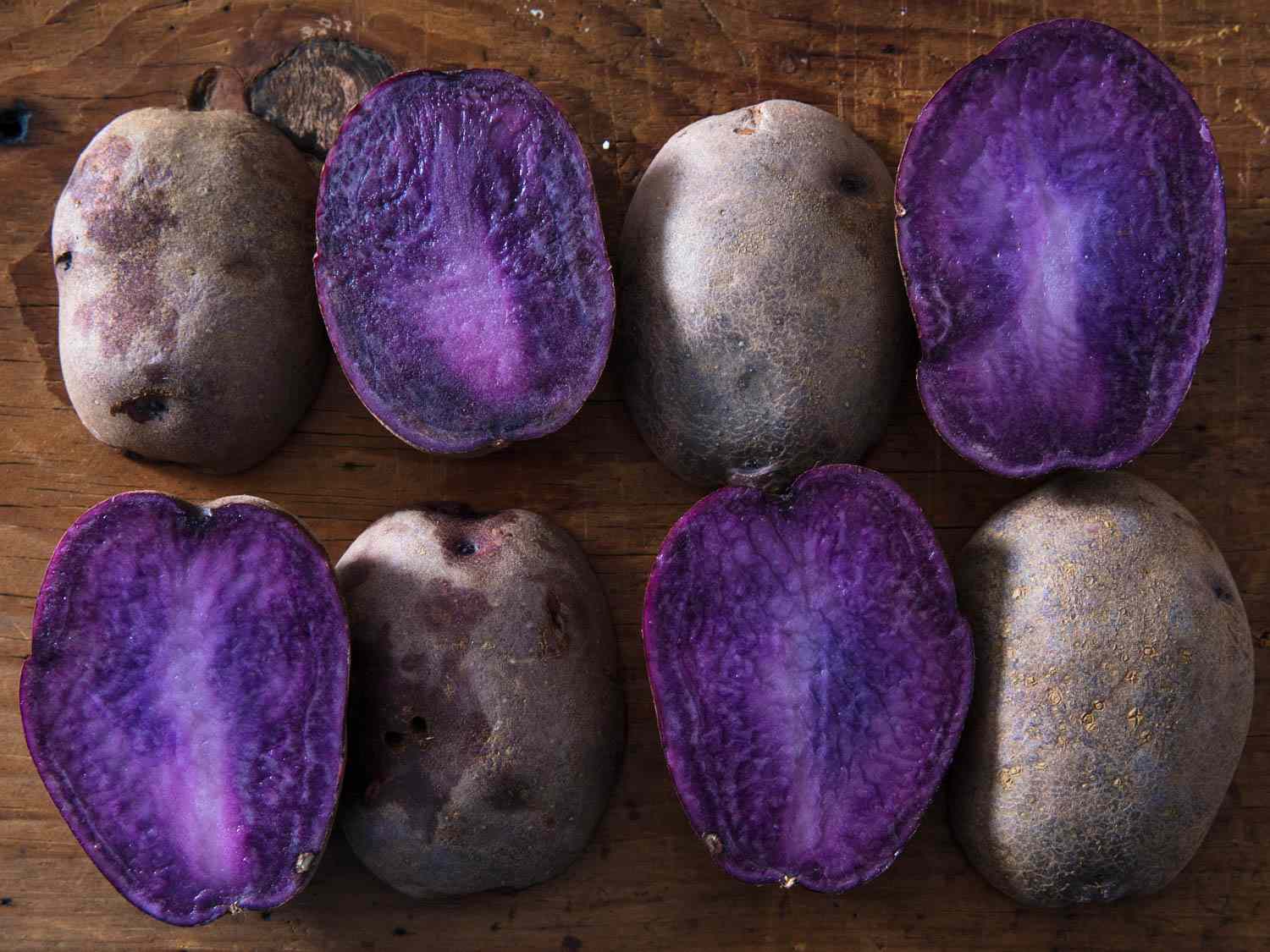Deep purple potatoes, sliced in half to reveal the colorful interiors.