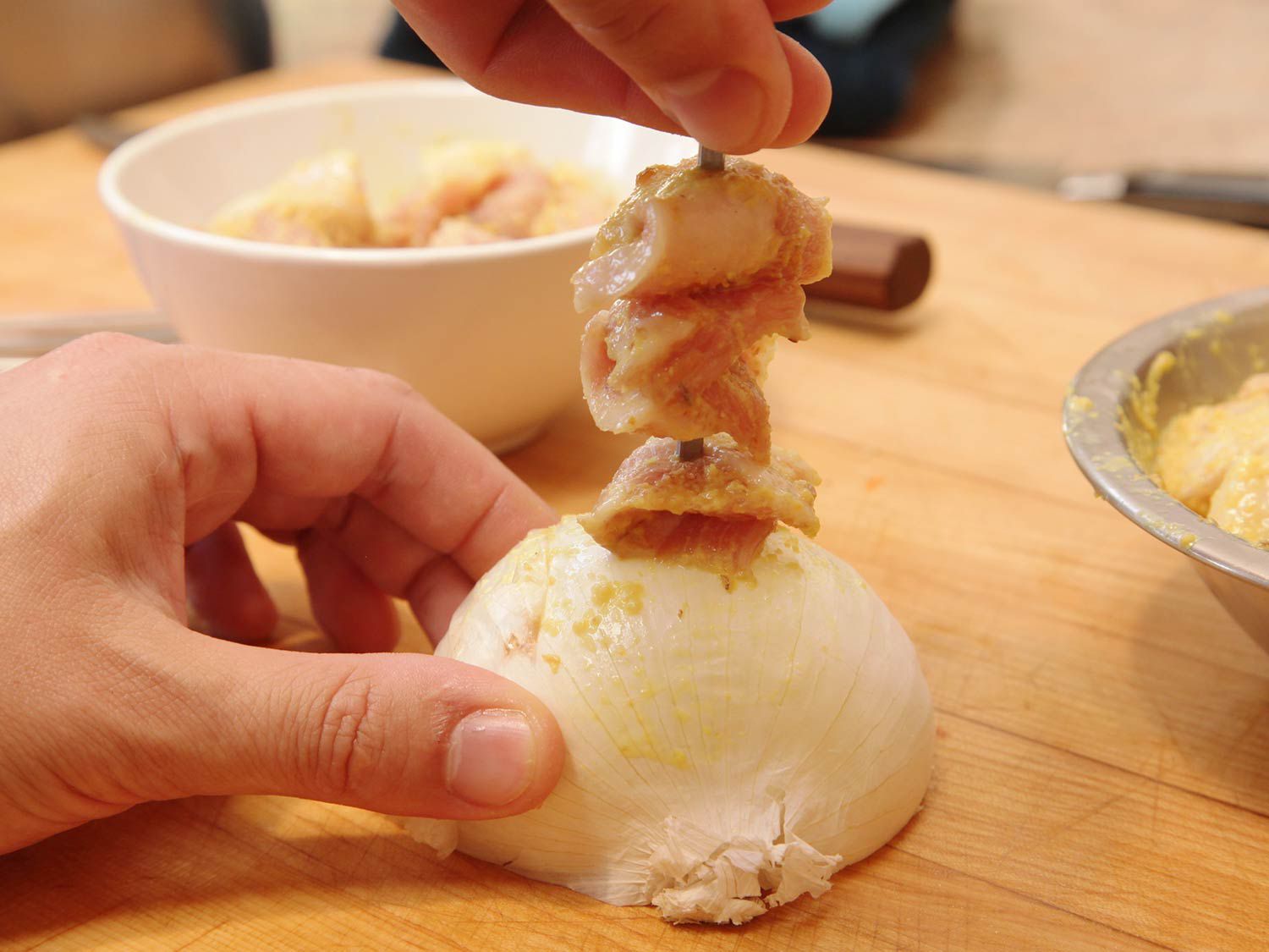 Threading marinated pork onto skewers for Balinese-style satay.