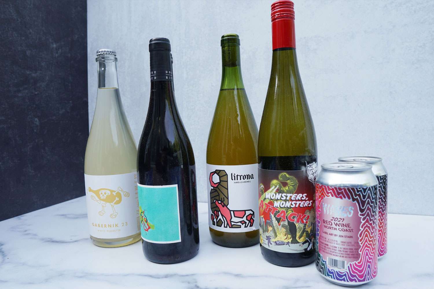 a number of wine bottles and a couple of cans of wine on a marble surface