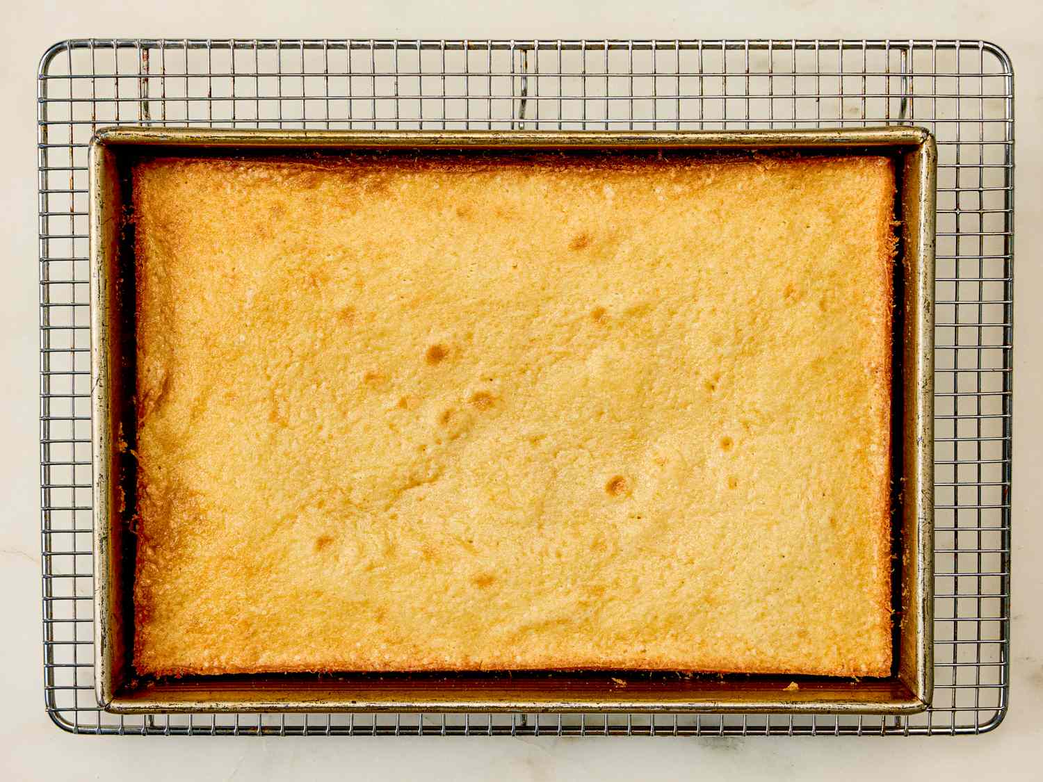 A baked rectangular cake cooling on a wire rack
