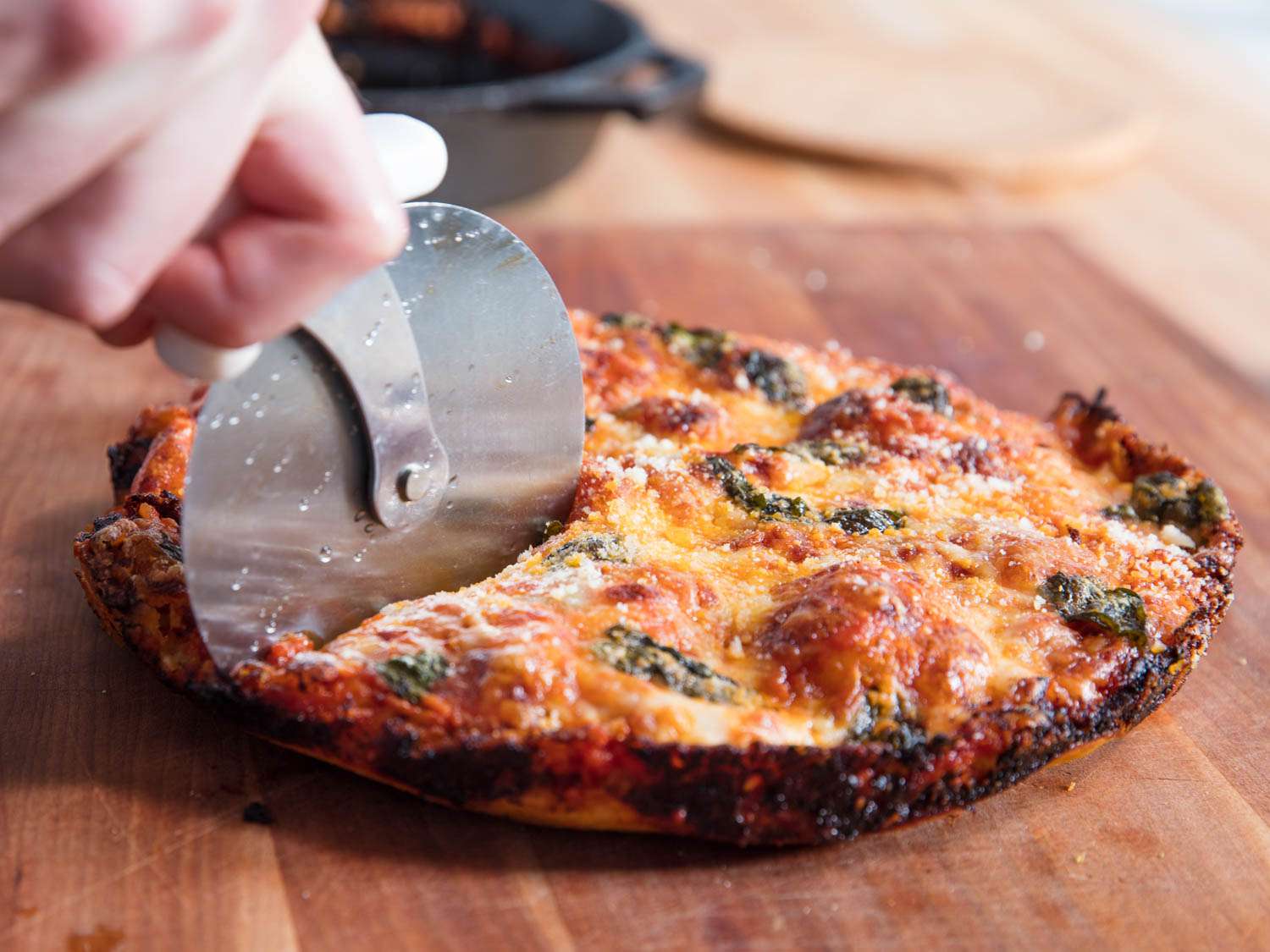 Slicing into a hot pan pizza with pizza cutter.