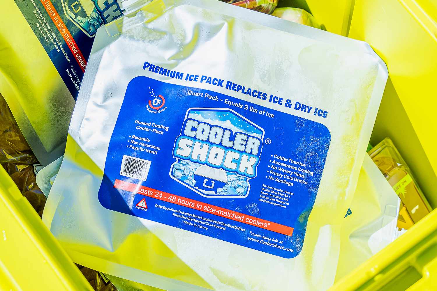 A Cooler Shock ice pack in a yellow cooler, with a closeup on the label