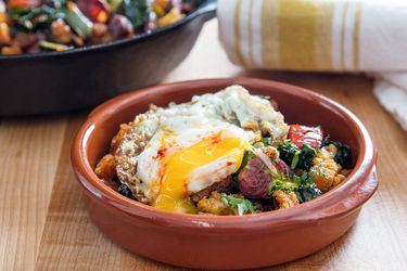 A bowl of migas topped with a fried egg with a runny yolk.