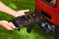 A person adding wood to the fuel chamber of the Pit Boss Vertical Propane Smoker