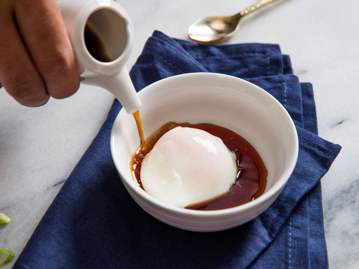 Author pouring chilled broth into a bowl containing an onsen egg.