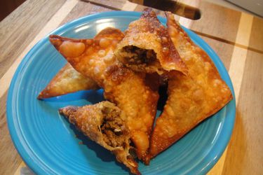 A plate of Somali sambusas, with one broken open to show the beef filling. 
