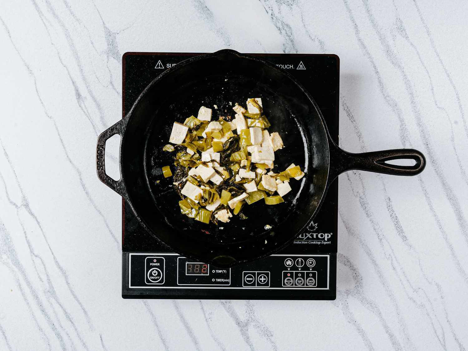 Minced pickled greens, bean curd, and sugar in a medium non-stick pan