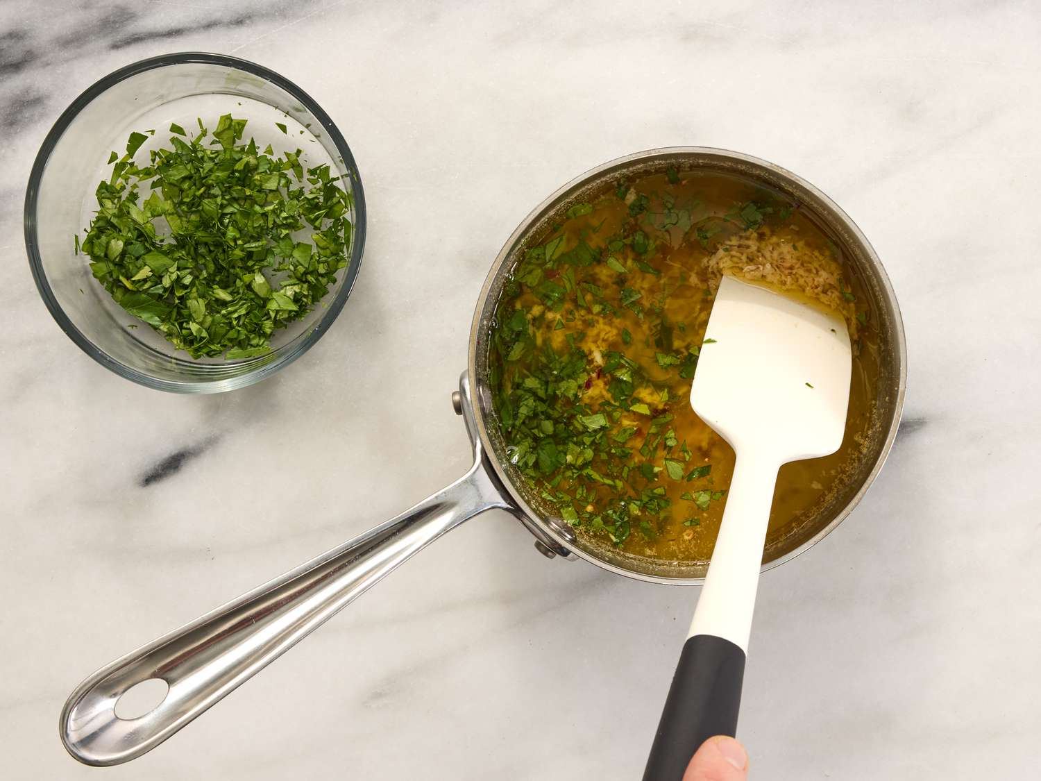 mixing parsley into garlic butter mixture in saucepan 