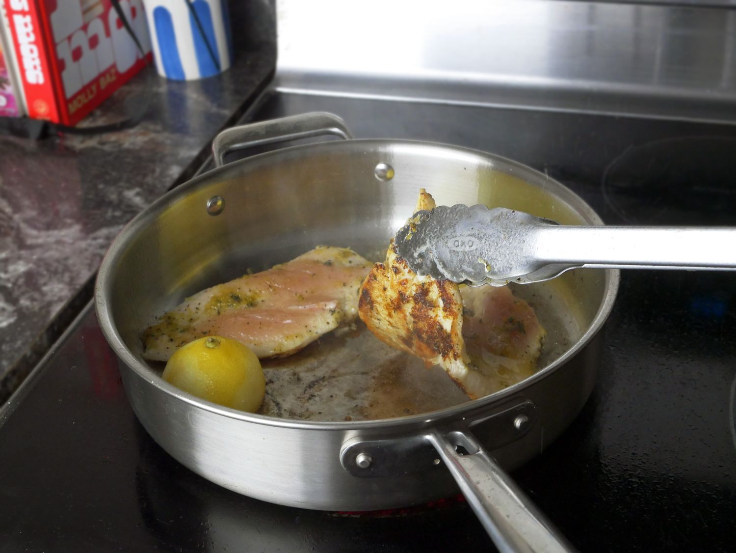 a person flipping chicken in a saute pan