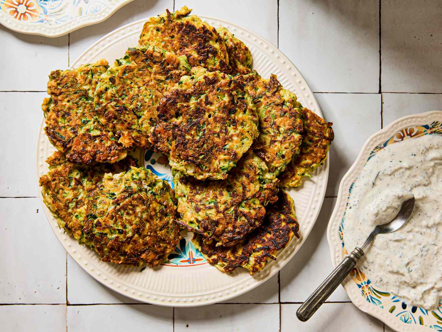 Plate of fritters next to a bowl of dip with a spoon