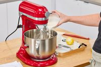 A person pours cream into the KitchenAid 7 Quart Bowl Lift Stand Mixer