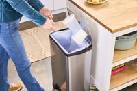 A person throws plastic containers into the simplehuman 38-Liter Brushed Stainless Steel Steel Trash Can with Lid