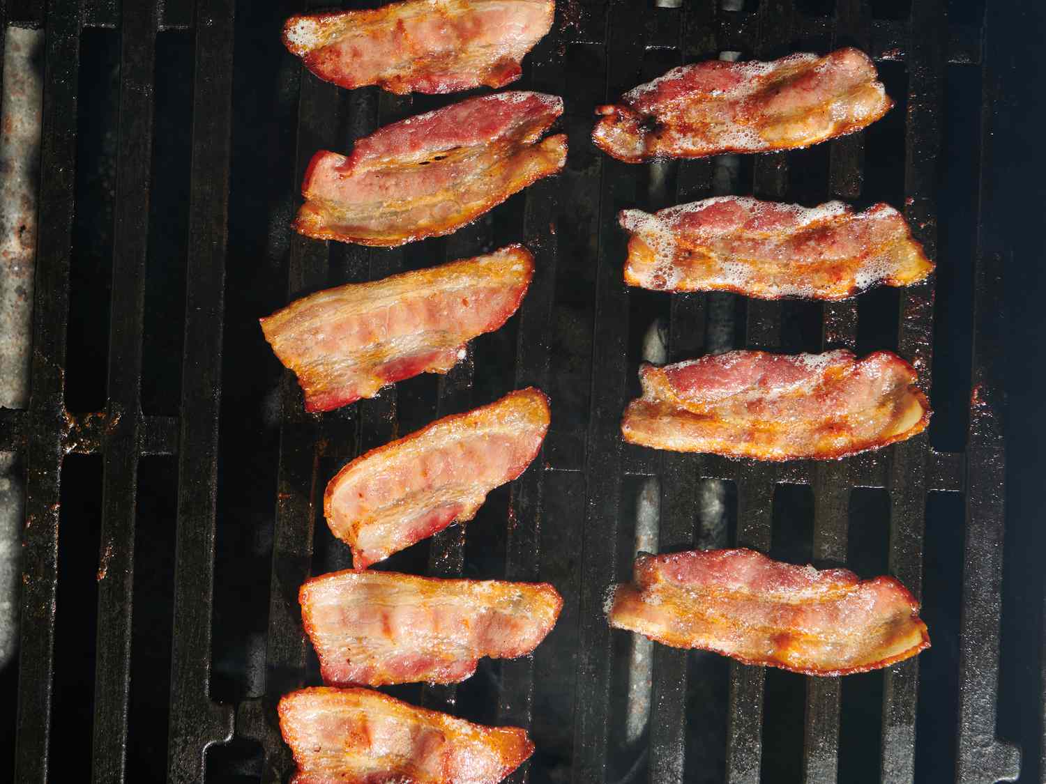 Bacon cooking in between hot and cool sides of grill