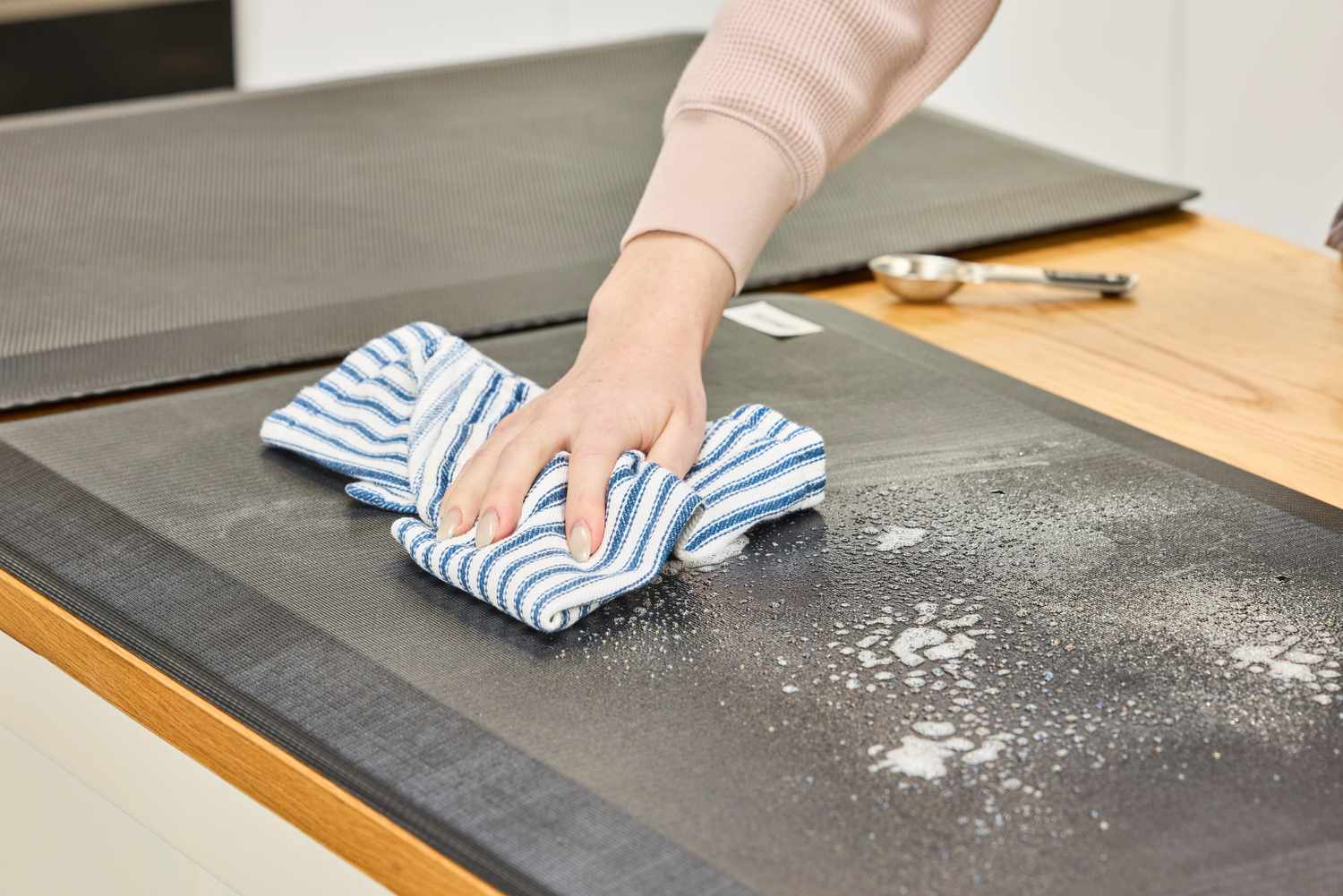 A person wipes cleaning solution off of the ComfiLife Anti-Fatigue Floor Mat