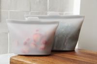 Two reusable silicone bags filled with berries and kale