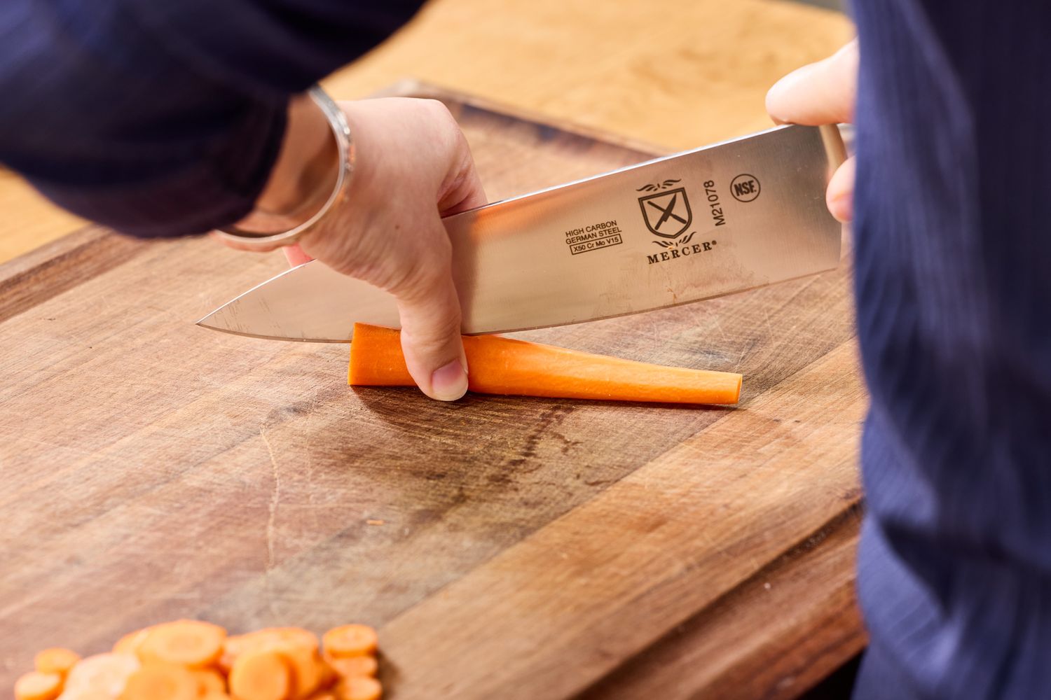 The Mercer Culinary 8-Inch Genesis Chef's Knife is used to halve a carrot