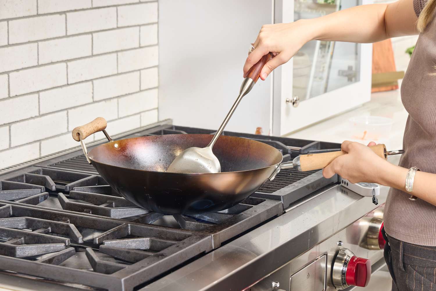 A person cooks in the Joyce Chen Carbon Steel Wok on a stovetop