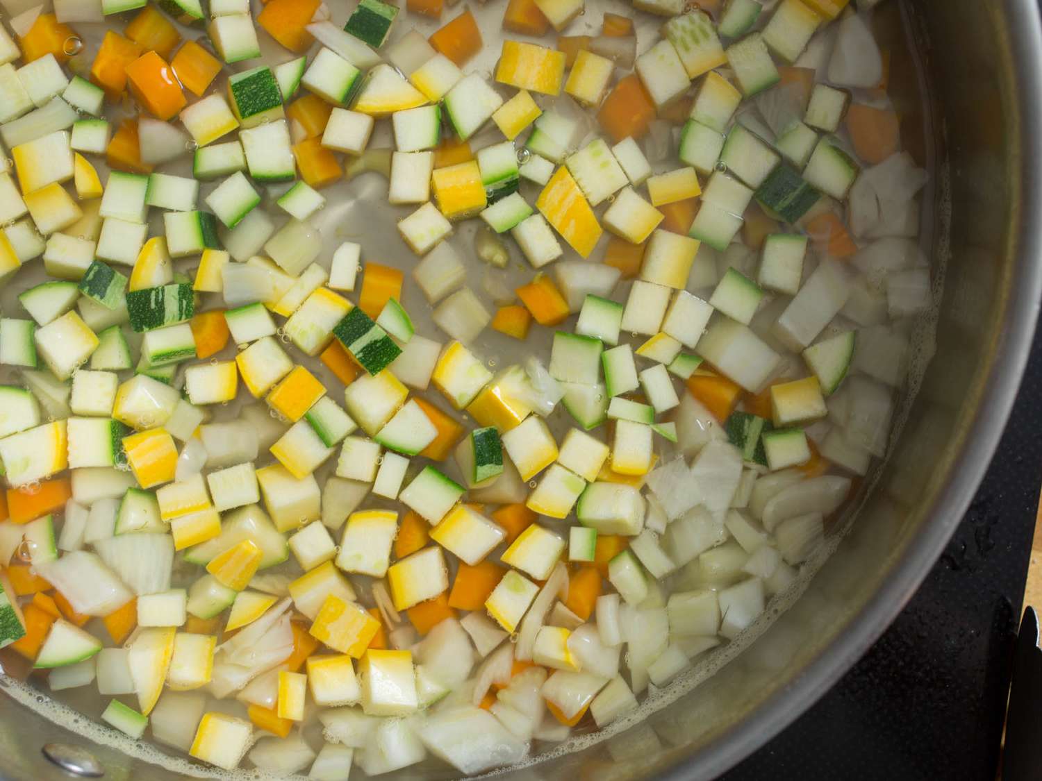 Diced squash, carrots, onion, and fennel in a clear broth.