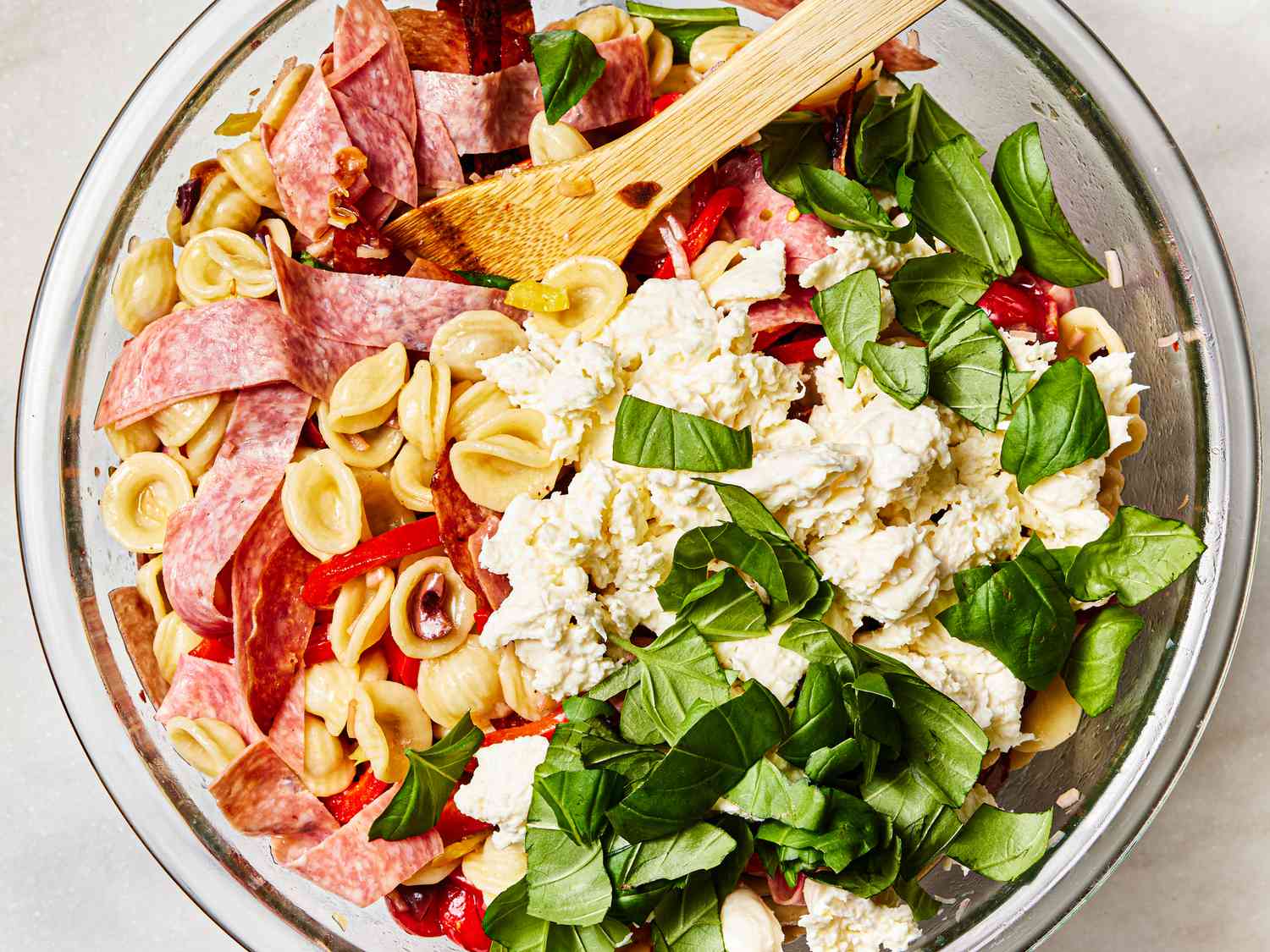 Mozzarella added to bowl with pasta salad 