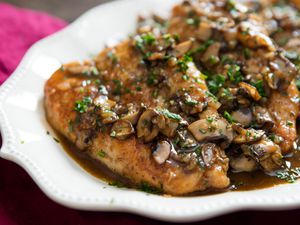 A chicken marsala covered in mushroom and resting on a plate