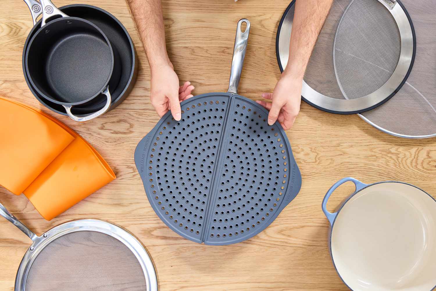 a person placing the williams sonoma splatter screen on a skillet