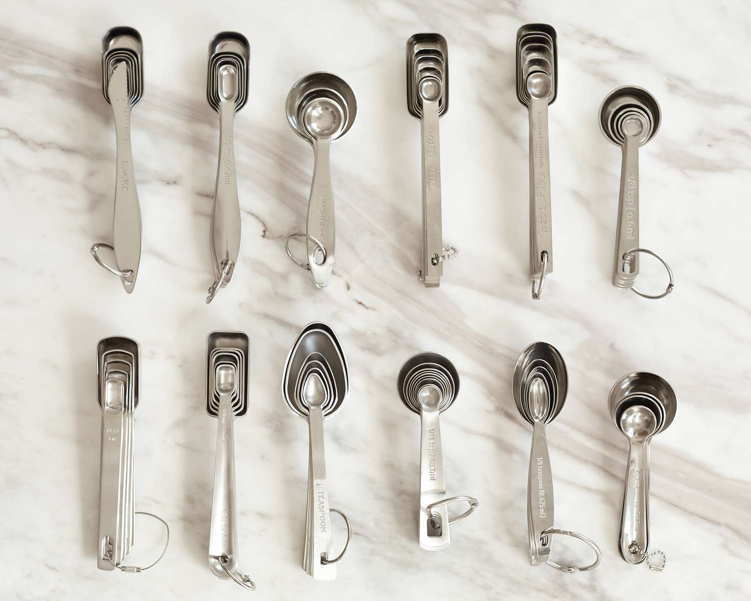 A number of measuring spoon sets on a marble surface