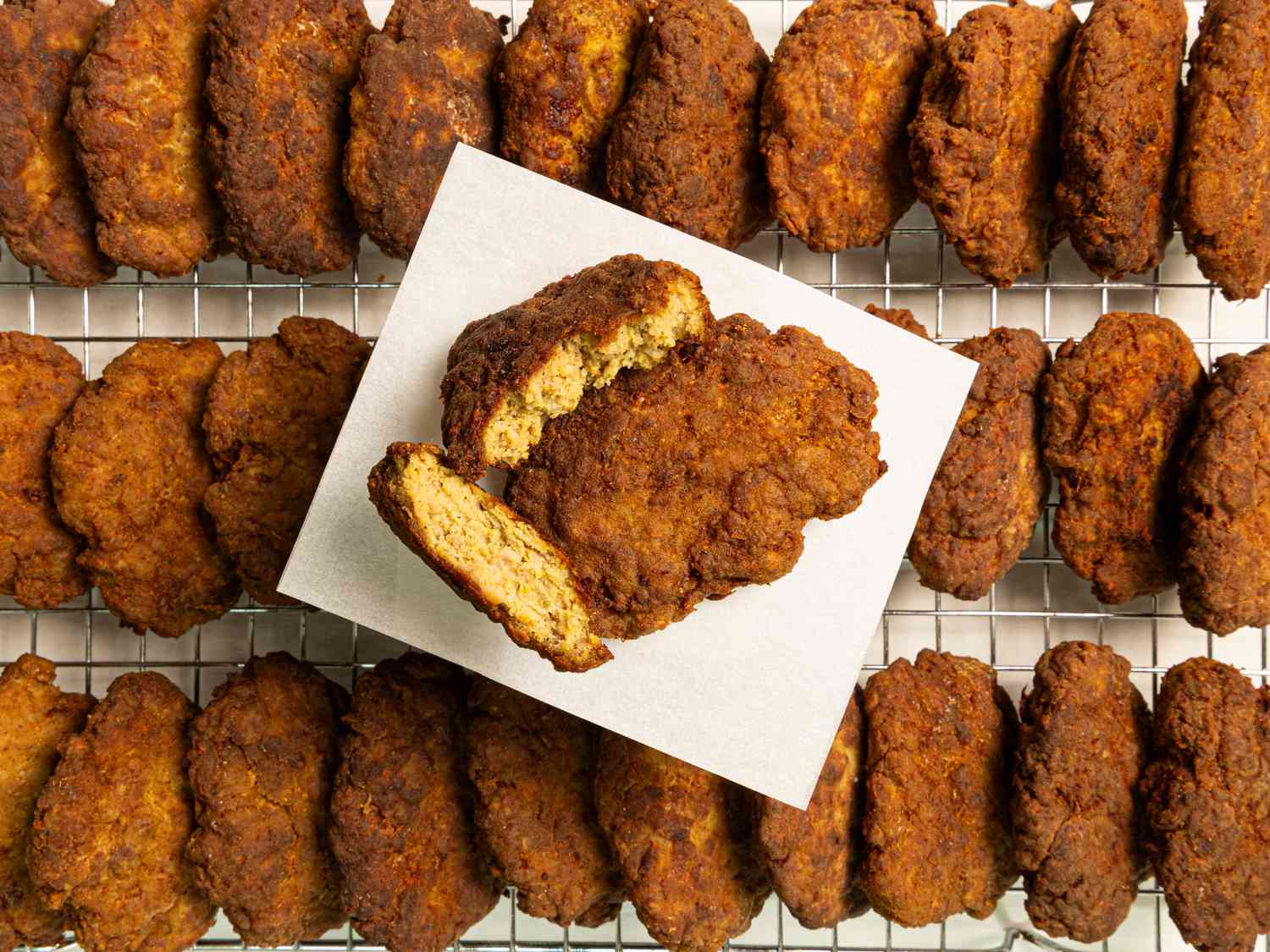  A kotlet split in half resting on a white plate on top of other finished kotlets 