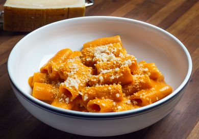 A white bowl of penne alla vodka sprinkled with cheese