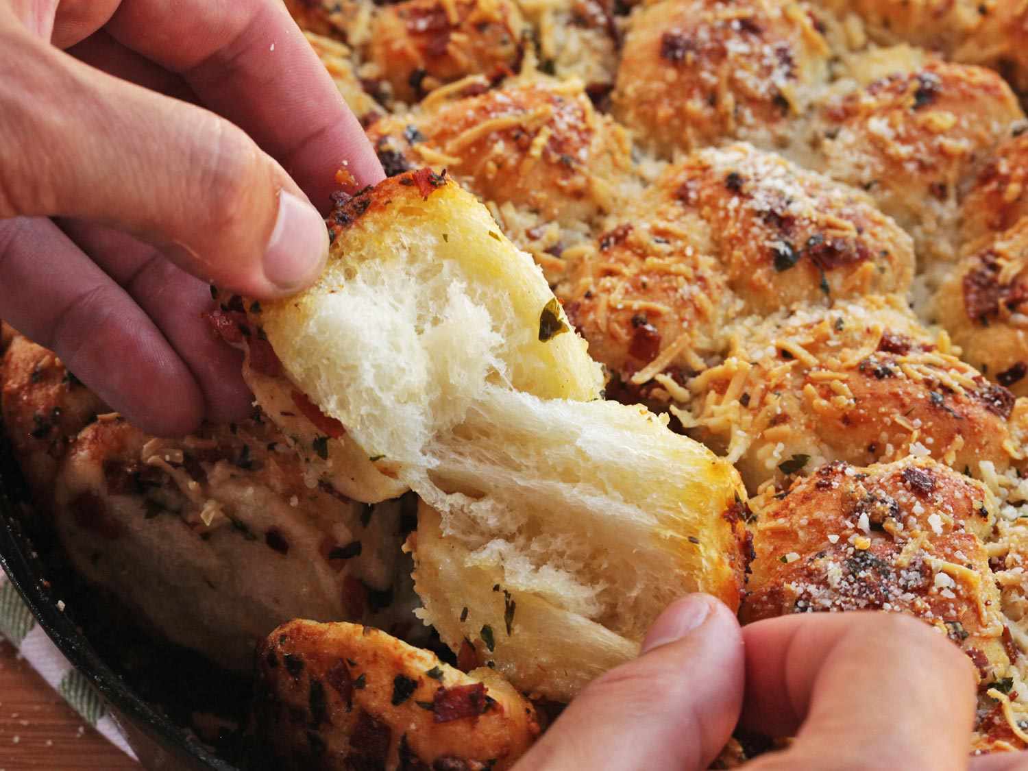 Closeup of a tender pepperoni garlic knot being torn in two