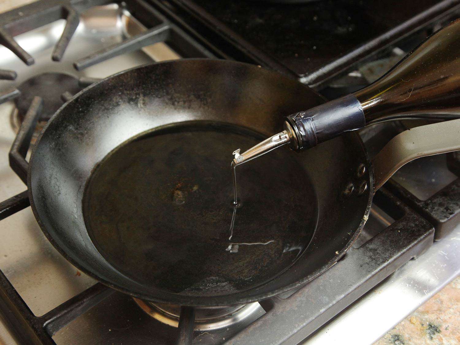 Pouring oil into a carbon steel skillet.