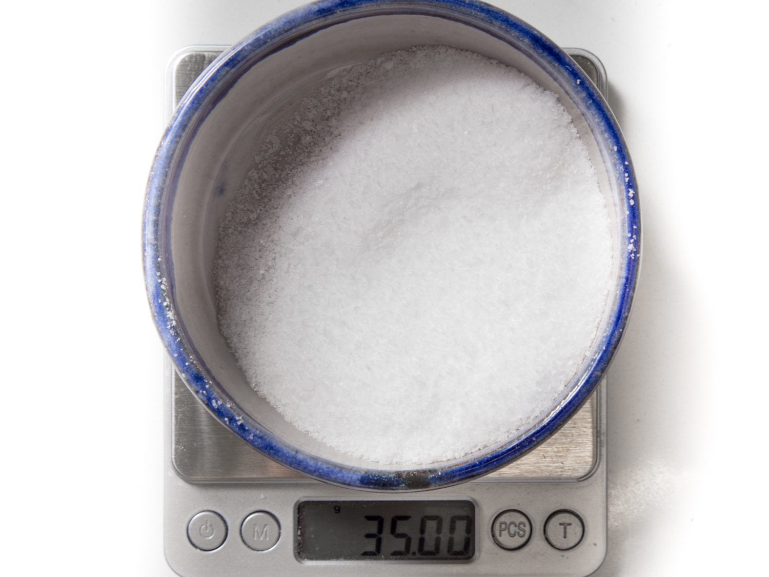 Overhead view of a bowl of salt sitting on a scale.