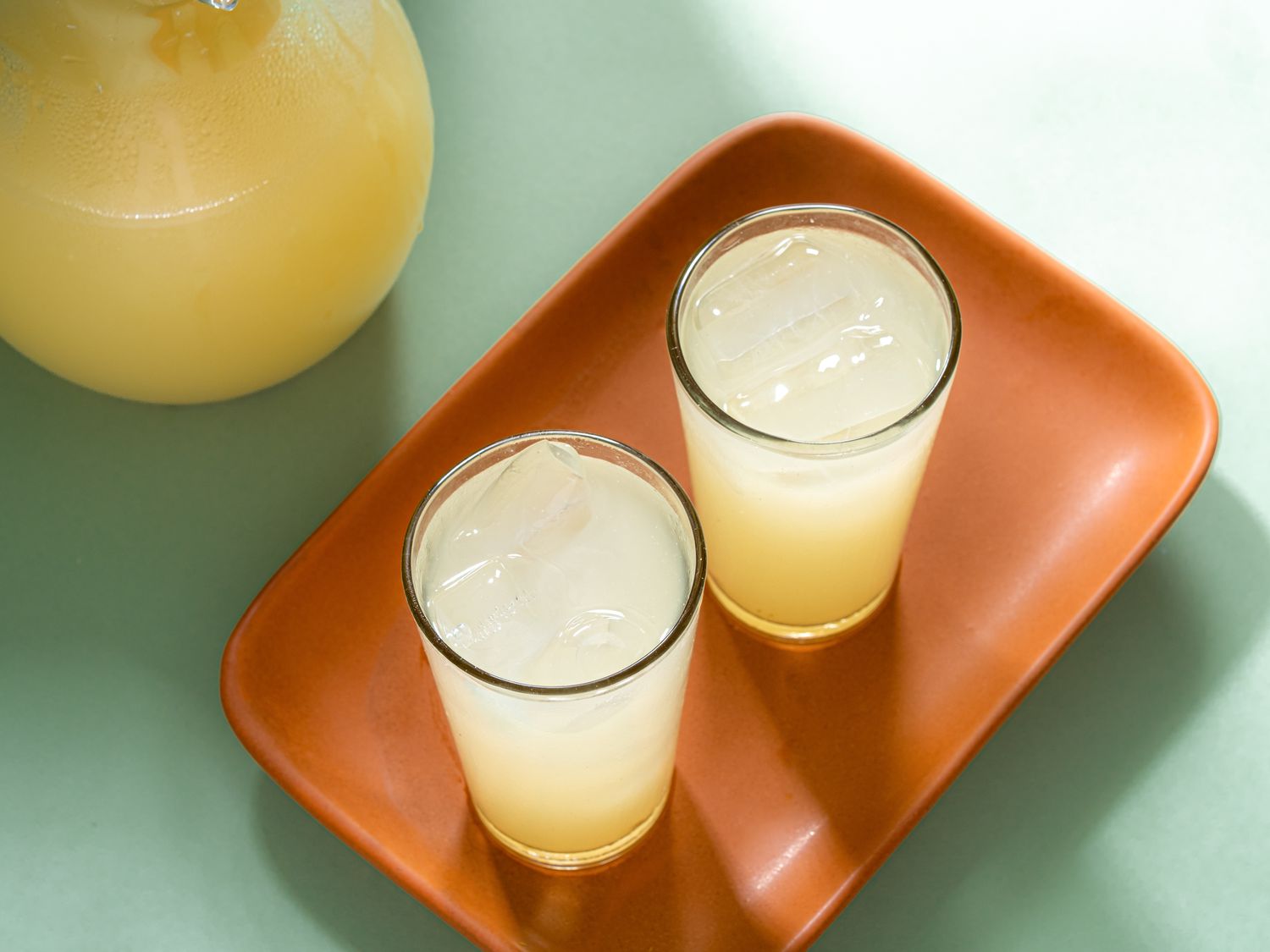 Two glasses of lemonade on an orange tray