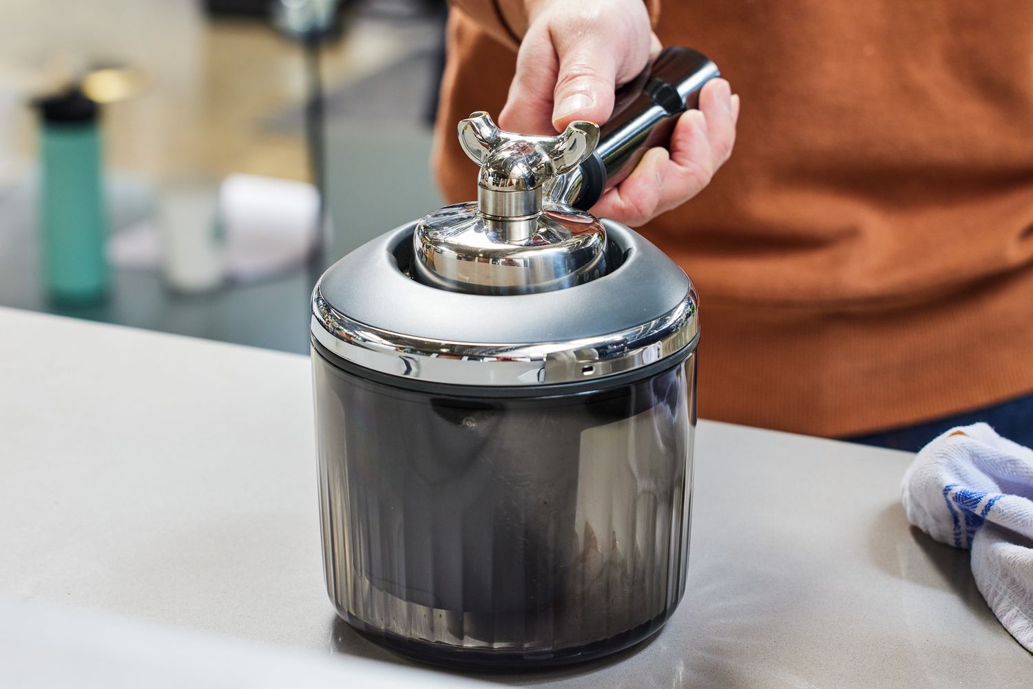 A person holding a portafilter in the Breville puck sucker.