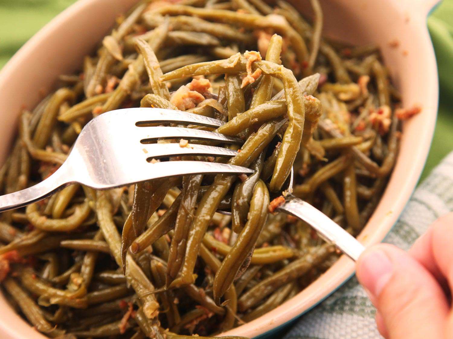 Serving finished bacon-braised green beans with a fork and spoon