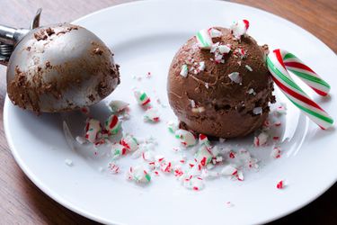 A copp of spiced dark chocolate and candy cane ice cream, dusted with crushed candy canes.