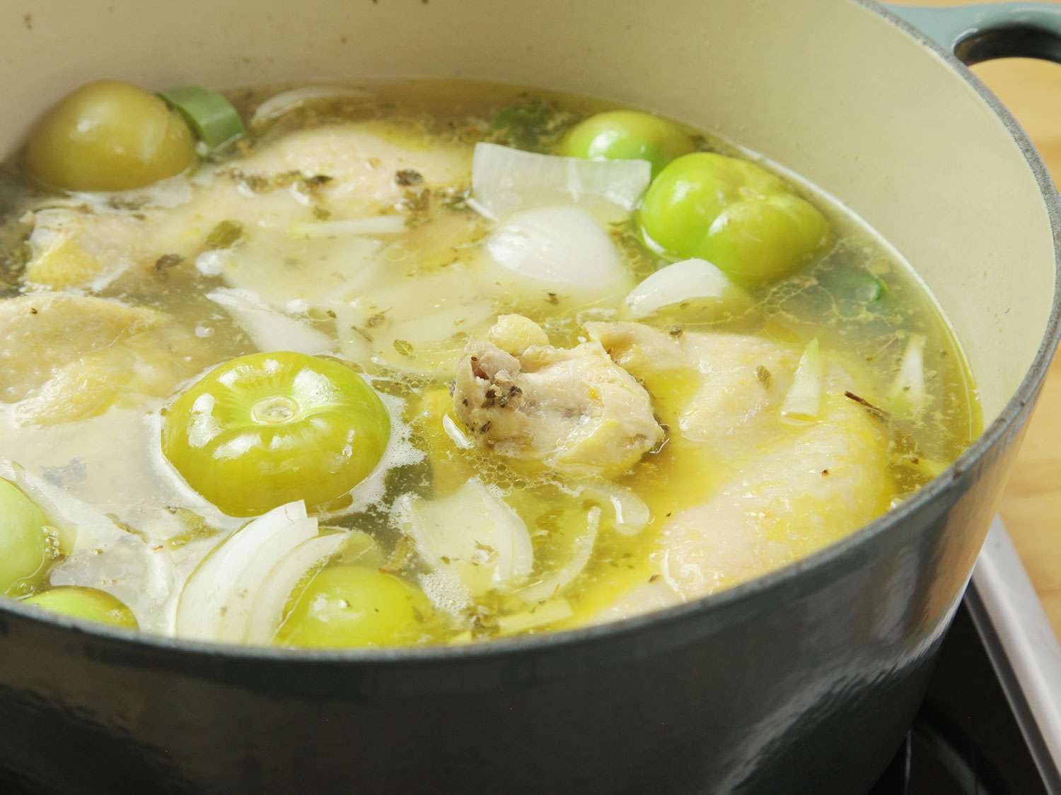 Chicken, tomatillos, and aromatics are brought to a simmer for pozole.
