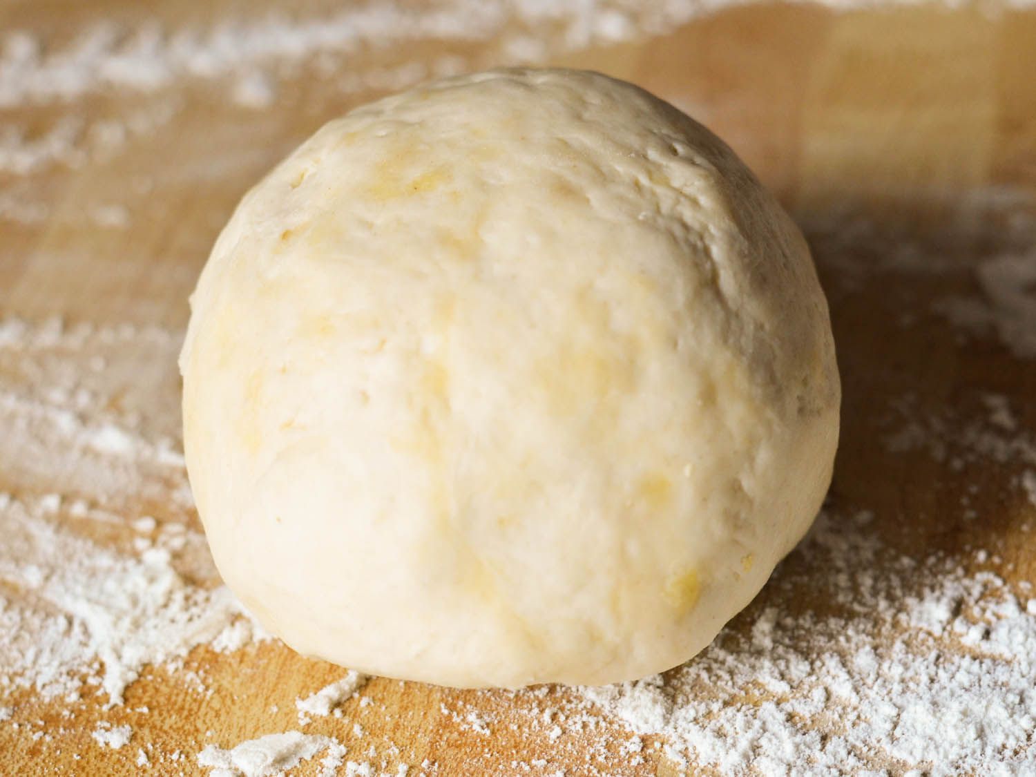 A ball of pierogi dough on a floured surface.