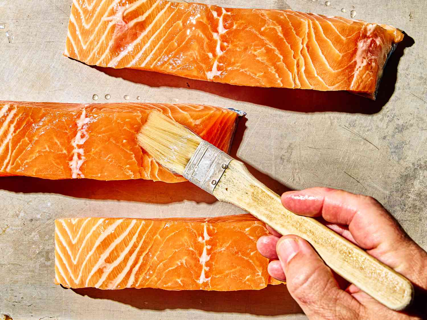 Overhead view of brushing salmon with oil