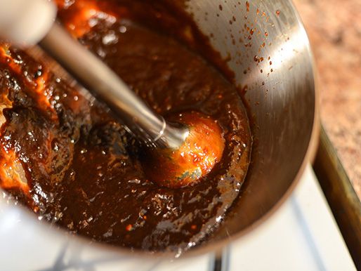 Closeup of the sauce being puréed with an immersion blender.