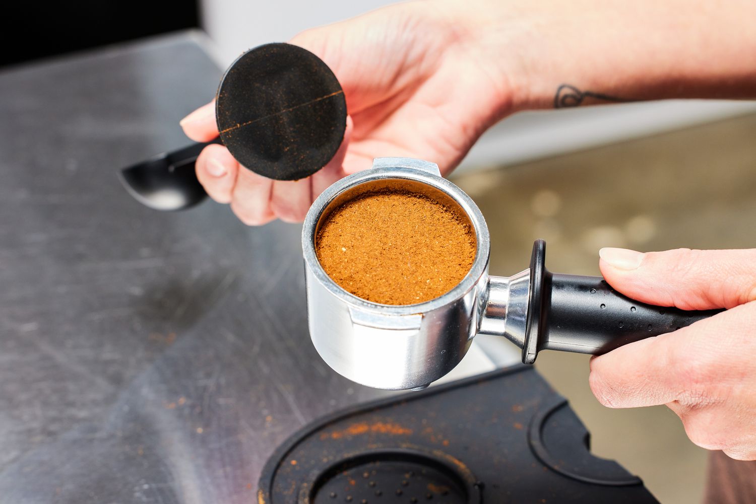 A person showing the inside of a portafilter filled with grounded coffee that will go inside of the De'Longhi Stilosa Espresso Machine