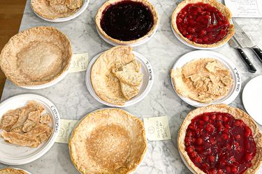 Various pie crusts and fruitfilled pies arranged on a table