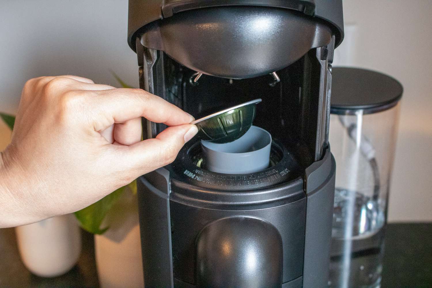 A hand placing a Nespresso capsule into a Nespresso