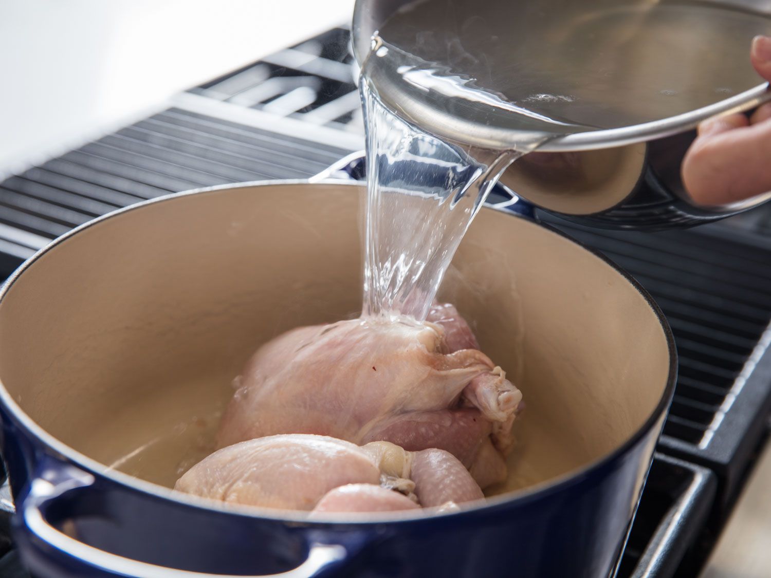 Adding broth to pot to cook samgyetang.