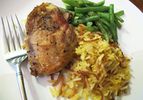 Closeup of skillet chicken with homemade Rice-A-Roni and green beans, served on a white plate.