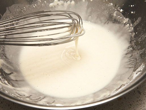 A whisk mixing a batter in bowl that chicken wings will be covered in. 