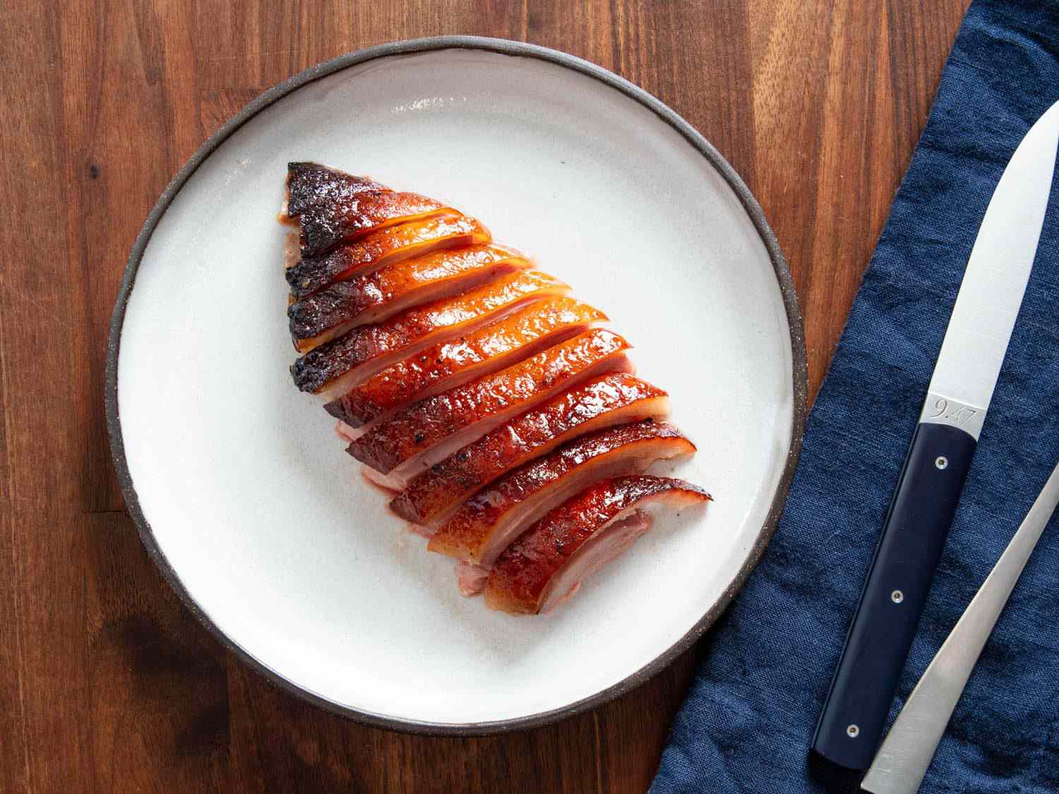 Overhead of sliced koji roast duck breast on a dinner plate.